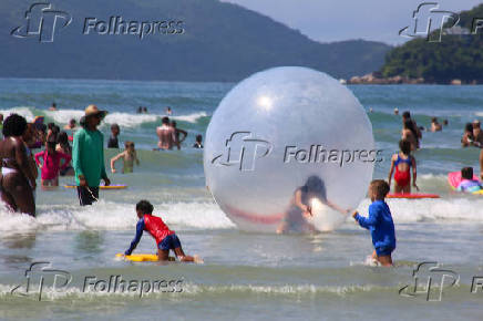 Crianas usam bolhas e colches inflveis dentro do mar, na praia Grande