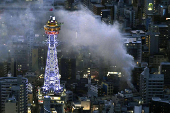 Smoke rises from a fire site at a commercial building near a famous tourist landmark Tsutenkaku Tower, in Osaka