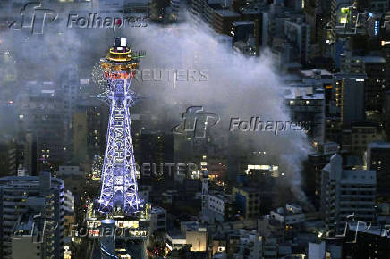 Smoke rises from a fire site at a commercial building near a famous tourist landmark Tsutenkaku Tower, in Osaka