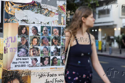 People make their way past images of those taken hostage or killed during the deadly October 7 attack, in Tel Aviv