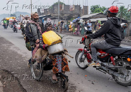 Internally displaced civilians from the camps in Munigi and Kibati, carry their belongings as they flee to Goma