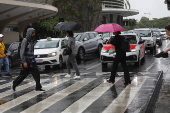 Pedestres se protegem da chuva que cai na regio do Aeroporto de Congonhas