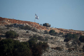 Israeli soldiers stand under an Israeli flag in southern Lebanon, near the Israel-Lebanon border