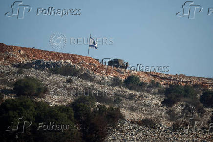 Israeli soldiers stand under an Israeli flag in southern Lebanon, near the Israel-Lebanon border