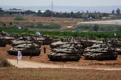 Israeli soldiers walk next to tanks near the Israel-Gaza border, amid the ongoing conflict between Israel and the Palestinian Islamist group Hamas, in southern Israel