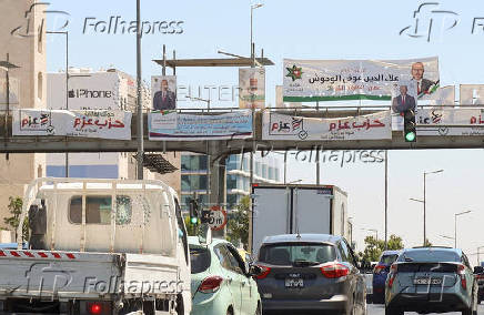 Cars pass near banners and pictures of candidates running in the country's parliamentary election in Amman