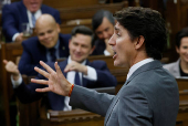 Canada's Prime Minister Justin Trudeau speaks while Conservative Party of Canada leader Pierre Poilievre pretends to play a violin in the background during Question Period in the House of Commons on Parliament Hill in Ottawa