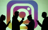 FILE PHOTO: Silhouettes of mobile users are seen next to a screen projection of Instagram logo in this picture illustration