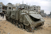 Palestinians look at damaged Israeli military vehicles left behind by Israeli forces in Rafah