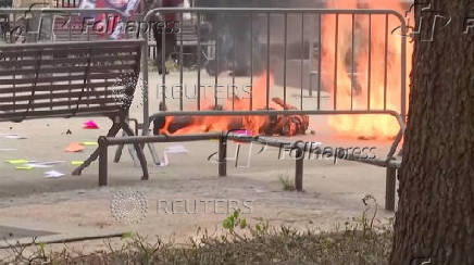 A person is covered in flames outside the courthouse where former U.S. President Donald Trump's criminal hush money trial is underway, in New York