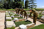 Israeli soldiers place Israeli flags on the graves of fallen soldiers, ahead of Israel's Memorial Day, at Mount Herzl military cemetery in Jerusalem