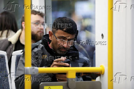 A man uses his smartphone on the tram in Manchester