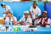 Electoral workers wearing school uniforms as costumes work at a polling station during regional elections in Jakarta