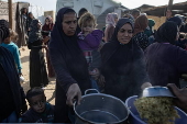 Displaced Palestinians collect donated food in Khan Yunis, southern Gaza