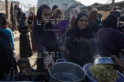 Displaced Palestinians collect donated food in Khan Yunis, southern Gaza