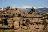 Israeli soldiers stand on a tank, amid cross-border hostilities between Hezbollah and Israel, by Israel's border with Lebanon