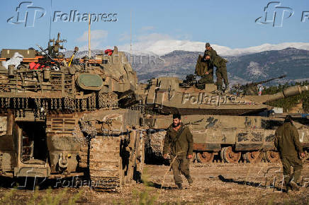 Israeli soldiers stand on a tank, amid cross-border hostilities between Hezbollah and Israel, by Israel's border with Lebanon