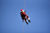 Guatemalan firefighter dressed as Santa Claus rappels down the Vacas Bridge to give toys to children, in Guatemala City