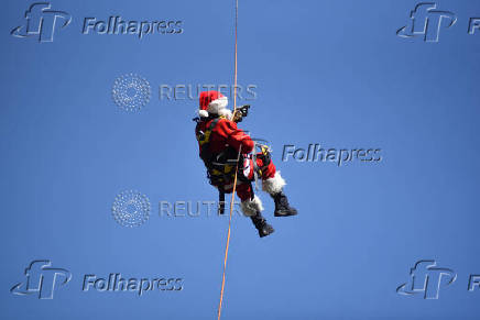 Guatemalan firefighter dressed as Santa Claus rappels down the Vacas Bridge to give toys to children, in Guatemala City