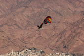 A person uses a parachute as the Jordanian city of Aqaba is seen in the background, in Eilat