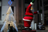 A homeless man walks near a Santa Claus decoration during Christmas Eve in downtown Sao Paulo