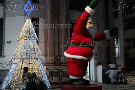 A homeless man walks near a Santa Claus decoration during Christmas Eve in downtown Sao Paulo