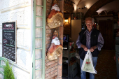 A man walks past dry-cured hams hung outside a grocery shop in Rome