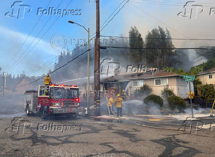 Firefighters work to stop a fire that damaged homes, in Oakland