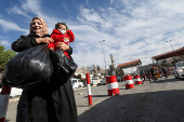 People make their way as they attempt to cross into Syria after Syrian rebels announced that they have ousted President Bashar al-Assad, near Masnaa Border Crossing