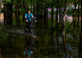 Man rides a bicycle across a flooded area in a park in Kyiv