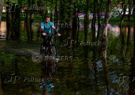 Man rides a bicycle across a flooded area in a park in Kyiv