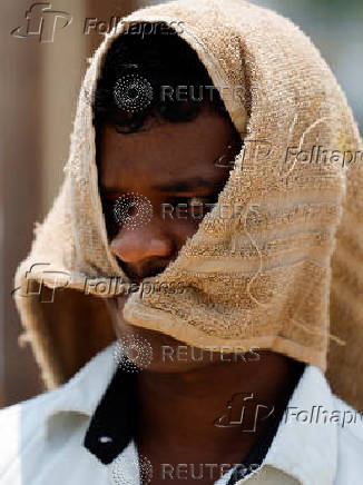 Man walks with a cloth covering his head on a hot day in Mumbai