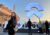 People pose for pictures in front of a sign of Nio at the electric vehicle (EV) maker's annual event NIO Day in Guangzhou