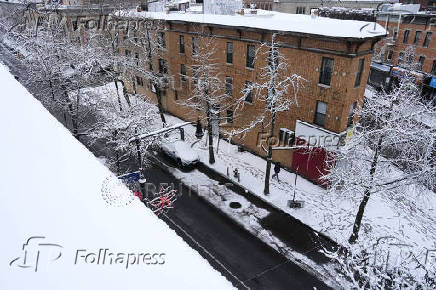 A person walks along a sidewalk during the city's first snowfall of the season, on the first day of winter in the Queens borough of New York City