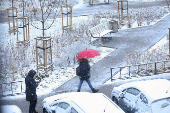 A woman uses an umbrella to cover herself from the snow, as she walks in Warsaw