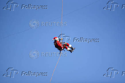 Guatemalan firefighter dressed as Santa Claus rappels down the Vacas Bridge to give toys to children, in Guatemala City