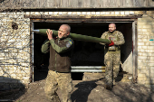 Ukrainian servicemen carry a rocket into a Grad MLRS before firing it towards Russian troops near a front line in the Donetsk region