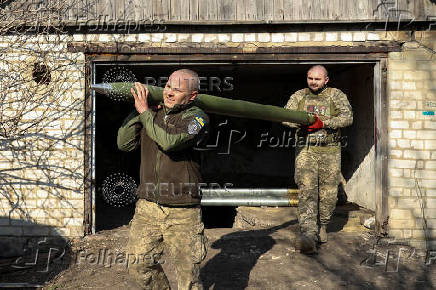Ukrainian servicemen carry a rocket into a Grad MLRS before firing it towards Russian troops near a front line in the Donetsk region
