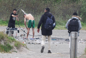 A migrant helps another to clean himself in a camp in Grande Synthe