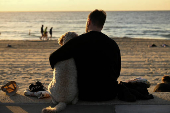 A man wraps his arm around a dog on ANZAC Day at Coogee Beach in Sydney