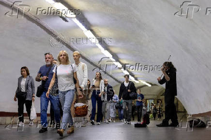 A man plays the violin as people walk in a subway station during morning rush hour in central Kyiv