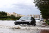Cars drive through water in a flooded street following heavy rains in Dubai