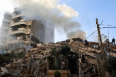 Civil defense members work at a damaged site, in the aftermath of Israeli strikes on Beirut suburbs