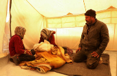 Displaced Syrian-Yazidi man Mohamed Nassro and his wife Shafiqa Saeeda, who fled the Aleppo countryside sit together inside a tent next to their grandchild in Tabqa