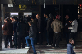 People wait in line in front of ATM, in Damascus