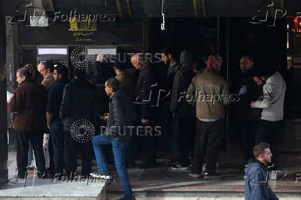 People wait in line in front of ATM, in Damascus