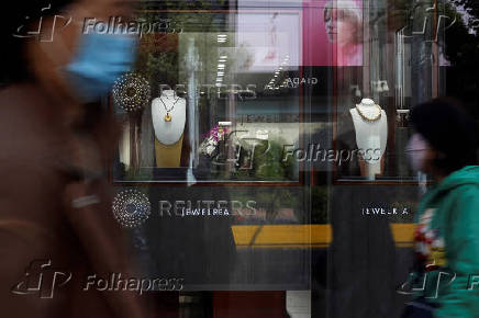 FILE PHOTO: People walk past gold jewellery at a display window of Chow Tai Fook jewellery store in Shanghai