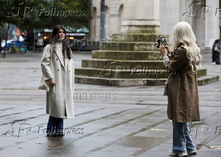 A woman takes a photo of her friend in Manchester