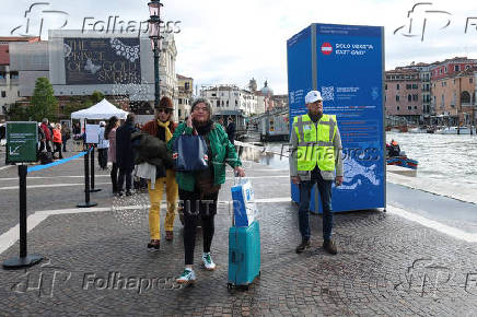 A controller officer directs the tourists to the info center where to register and pay the fee for day trippers introduced by Venice