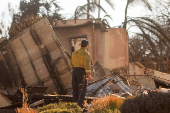 A person looks at a damaged house due to the Mountain Fire in Camarillo, California